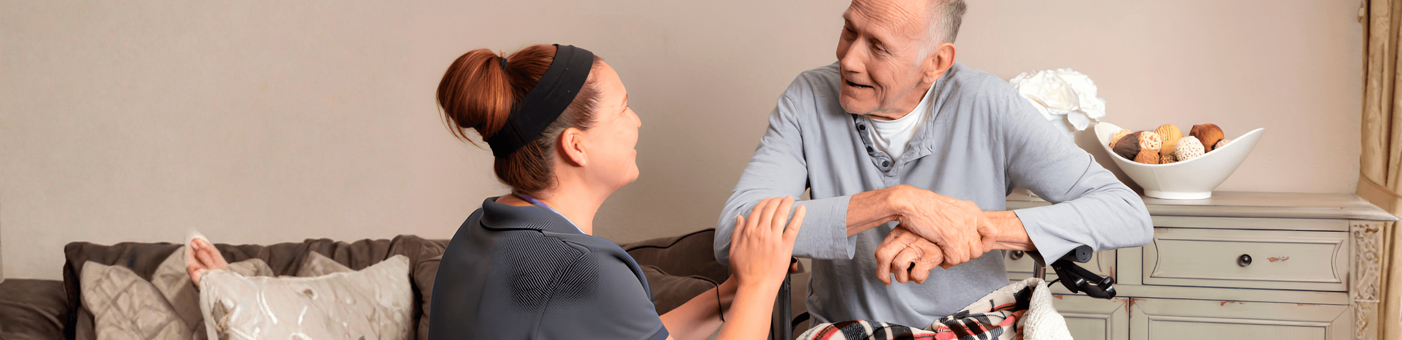 Home carer sitting with elderly man receiving palliative care at home in Nottingham, holding hands