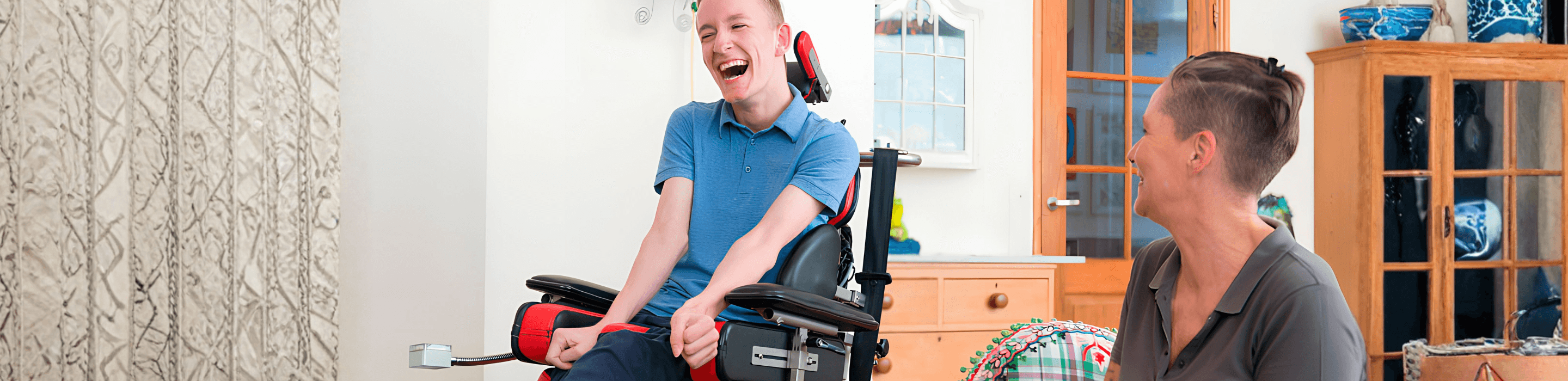 Supported living in Nottingham — a young man in a wheelchair laughing with his support worker at home